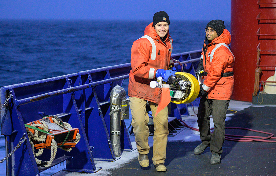 Two faculty wearing life jakcets standing on the deck of the research vessel Sikuliaq