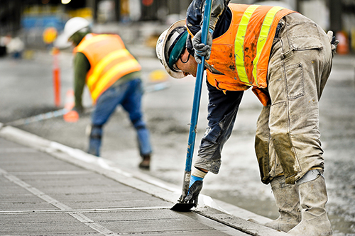 A construction worker working on a concrete road.