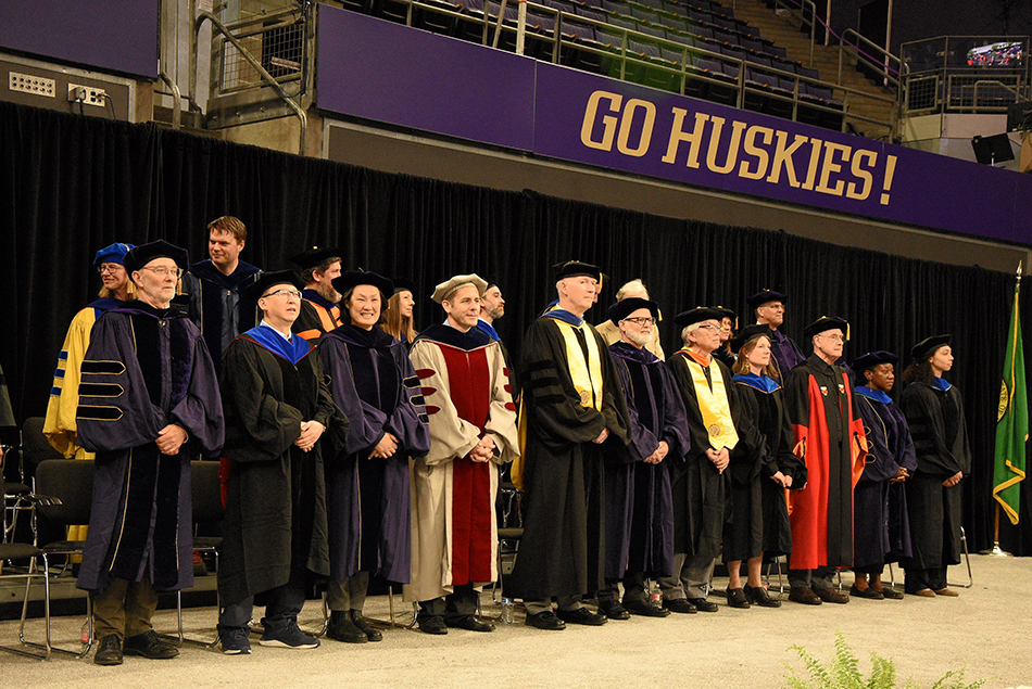 Group of CEE faculty members in academic regalia standing on stage.