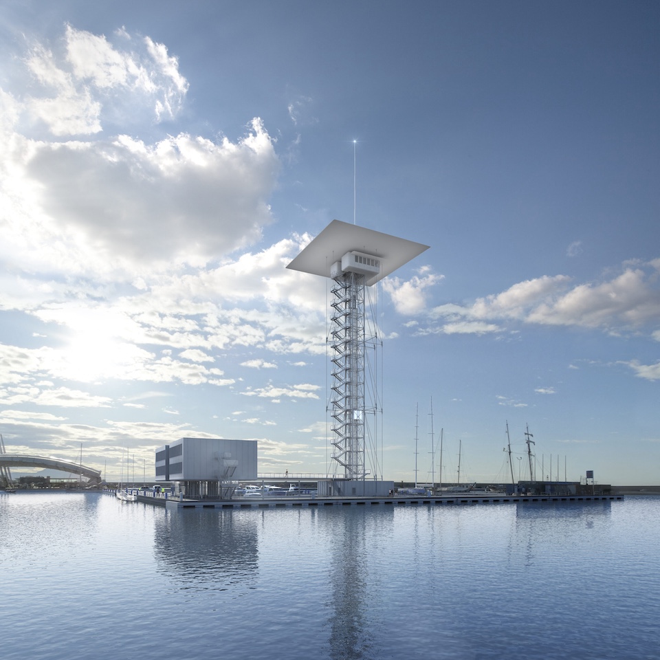 A tall tower and an adjacent rectangular building on water under a partly cloudy sky.