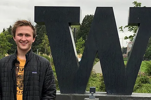 Adam Bogh standing in front of some greenery and a W