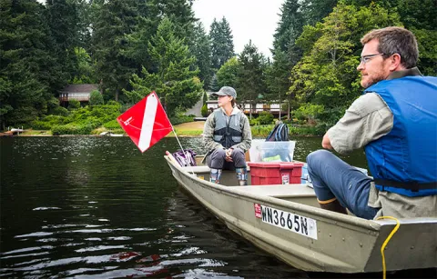 Two people sitting in a boat on a lake