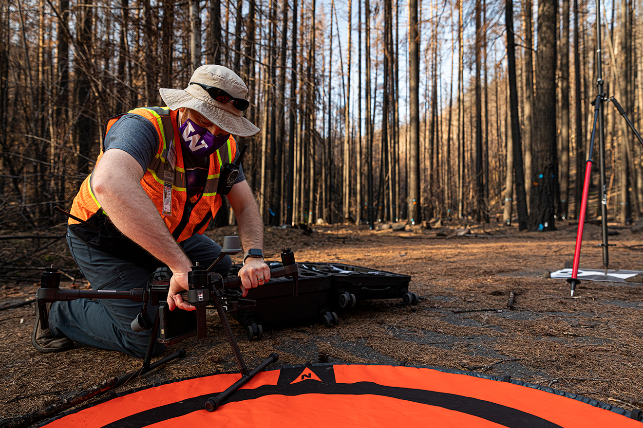 A researcher setting up a drone in the woods