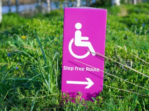 pink sign with person in wheelchair and words 'Step free Route'