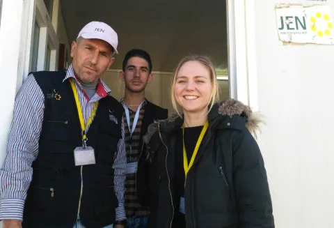 photo of Alumna Heta Kosonen with members of the JEN team standing in front of the office trailer at Mamilian IDP (internally displaced person) camp