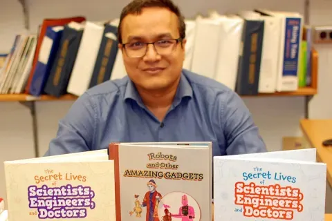 Man sitting at a desk showing three books