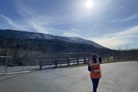 A person wearing an orange RAPID vest overlooks the Oso landslide area.