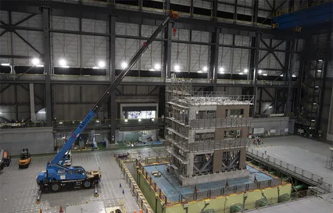 A shake table inside a warehouse with a crane next to it