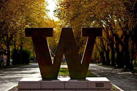 Bronze W with trees in the background