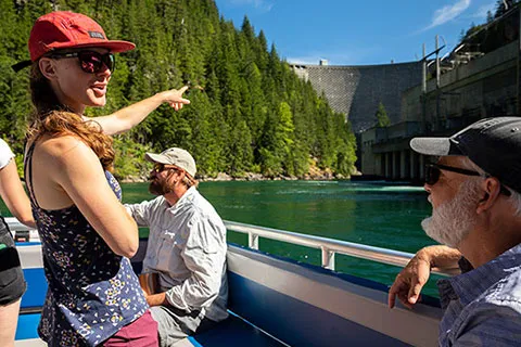 student pointing at a dam from a boat on a river